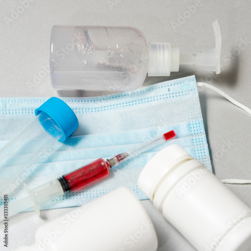 tablets in jars, antiseptic gel, disposable mask, syringe with a red vaccine. development of a vaccine against Covid-19 by scientists photo