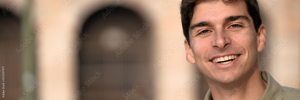 Portrait of young smiling man isolated on outside outdoor background