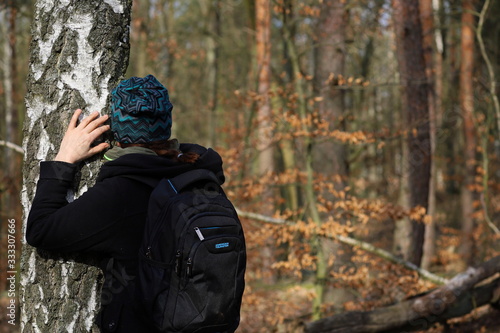 a woman on a walk in the woods hugs the tree, spring in Poland