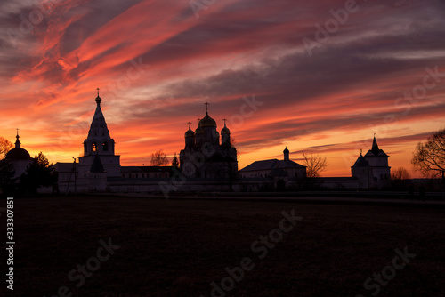 The black silhouette of the monastery against the bright sunset sky.