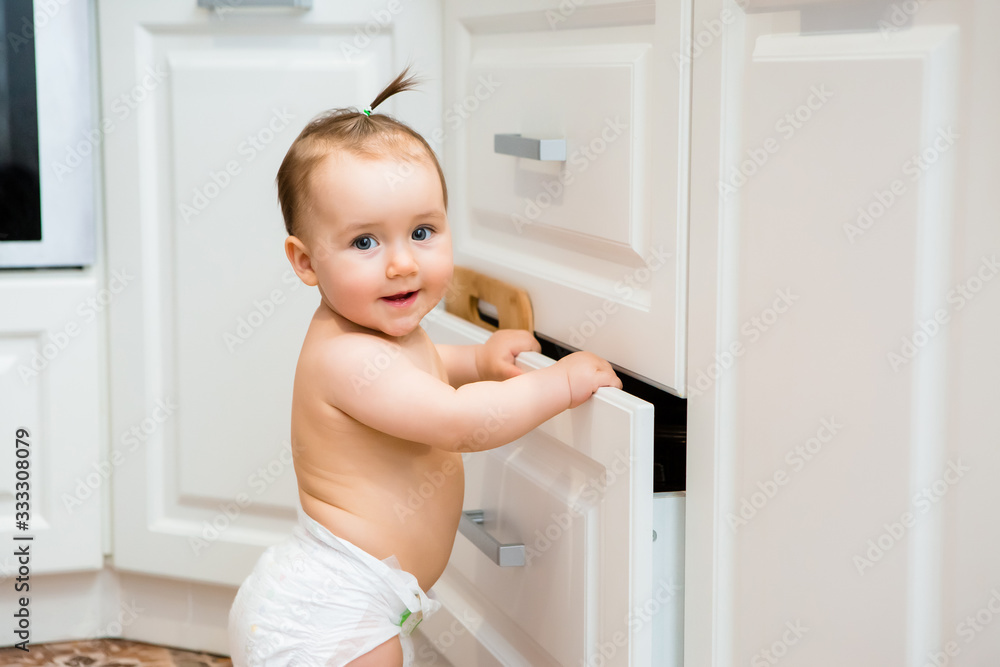 Happy baby girl smiling sitting in kitchen drawer with pans Happy baby girl smiling sitting in kitchen drawer with pans