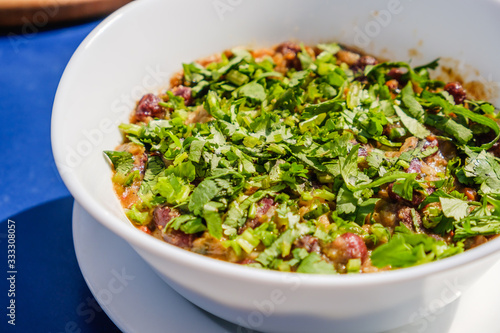 Lobio dish with red beans, spices and herbs. On blue table.