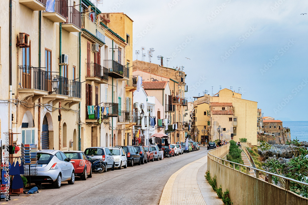 Cozy street with cars in Cefalu town Sicily