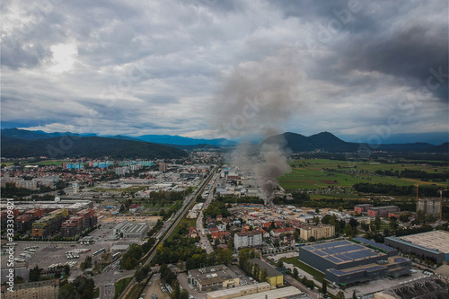 Aerial photo of a fire in industrial area of Stegne in Ljubljana, Slovenia. Dark plume of smoke is visble rising up from the place of ignition. Danger of pollution and respiratory problems for people.