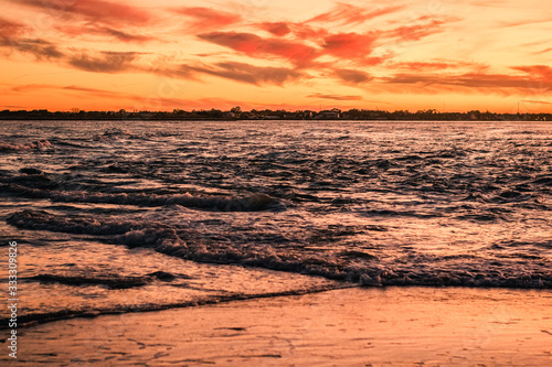 Sunset Colored Waves Crossing and Rippling, Pink Clouds in the Sky Behind