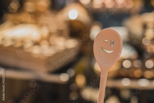 Wooden smiley face spoon outdoors. Image of a kitchen utensil making a smile on a sunny day. Good idea for cooking backgrounds. photo