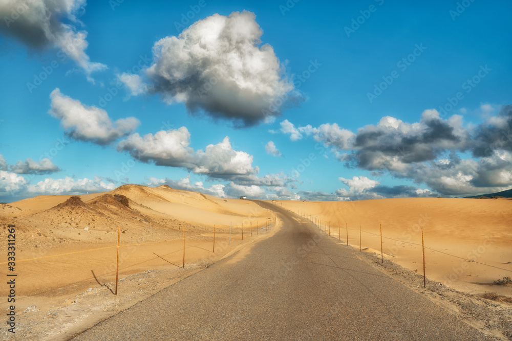 Road through sand dunes. Beautiful cloudy sky on a horizon