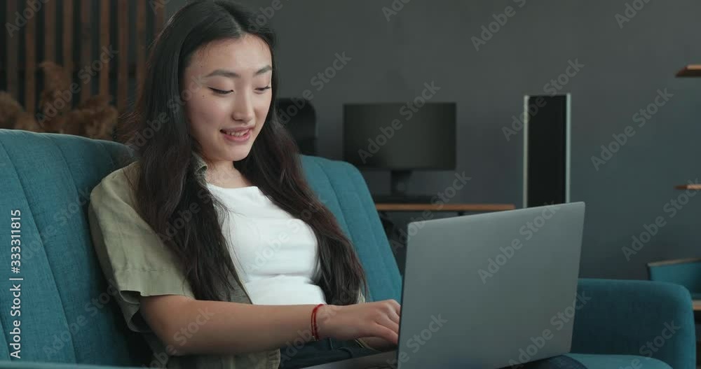 Young Chinese Woman using Laptop PC while standing at Home. Chinese Woman is sitting at Home during Quarantine, using Technology while Inside Self isolation. Home quarantine. Coronavirus.Wuhan. China. Young Chinese Woman using Laptop PC while standing at Home. Chinese Woman is sitting at Home during Quarantine, using Technology while Inside Self isolation. Home quarantine. Coronavirus.Wuhan. China.