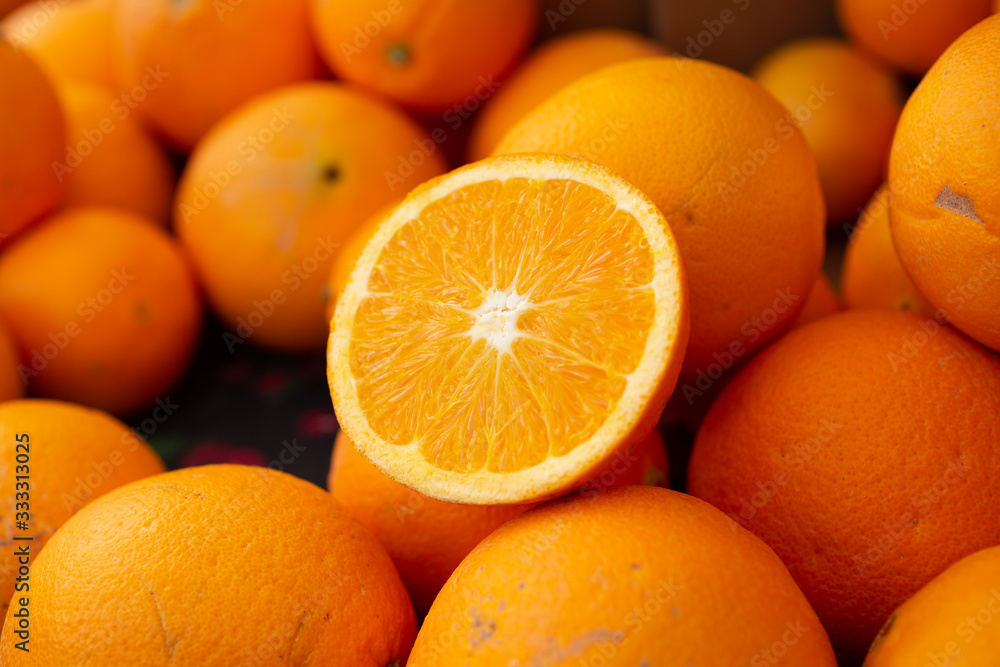 A view of a table full of navel oranges with one orange cut in half showing the segments inside, seen at a local farmers market. A view of a table full of navel oranges with one orange cut in half showing the segments inside, seen at a local farmers market.