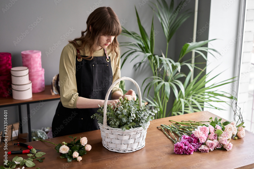 Floral shop concept . Florist woman creates flower arrangement in a wicker basket. Beautiful bouquet of mixed flowers. Handsome fresh bunch. Flowers delivery. Floral shop concept . Florist woman creates flower arrangement in a wicker basket. Beautiful bouquet of mixed flowers. Handsome fresh bunch. Flowers delivery.