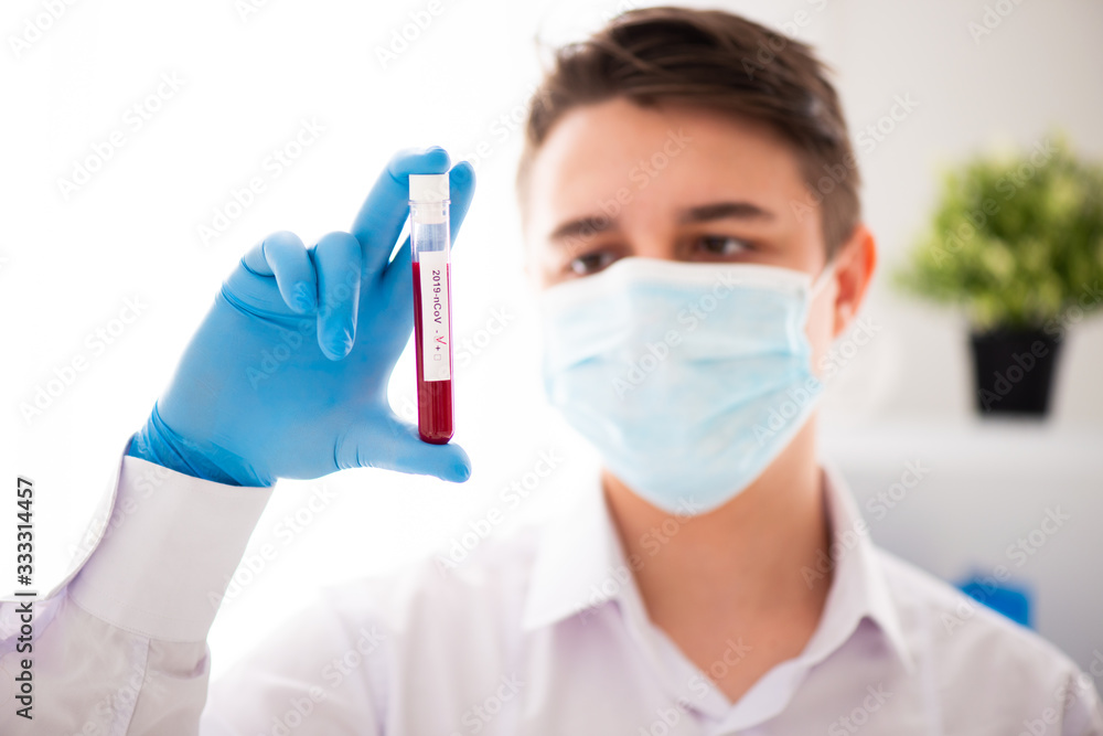 Test tube in male hand close up, doctor in medical mask holding vial with red liquid. Concept blood sample, coronavirus diagnostic, medical research Test tube in male hand close up, doctor in medical mask holding vial with red liquid. Concept blood sample, coronavirus diagnostic, medical research
