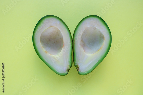 Avocados cut in halves. Yellow background. Top view. Healthy food concept