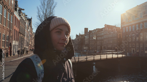 Photography Portrait of young pretty girl traveller enjoying spring sun in Amsterdam street,