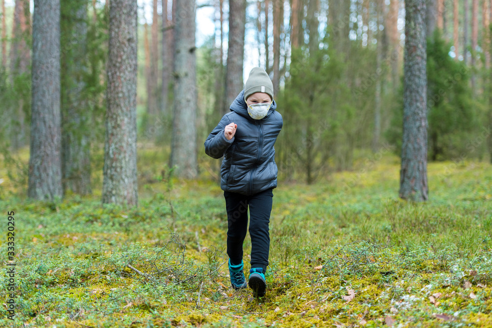 Fototapeta premium Little boy with a mask run in the forest. Corona virus quarantine
