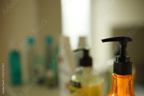 Closeup orange cream bottle with black dispenser on a shelf in the bathroom. © Omega