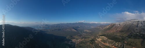 Aerial view of Delphi, Greece at sunrise, the Gulf of Corinth, Morning fog over mountains, hoarfrost on roofs, mountainside with layered hills beyond with rooftops in foreground