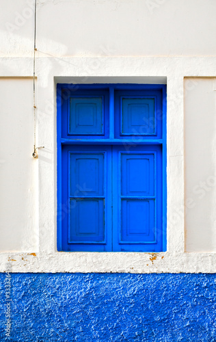 A blue window in a white wall, typical Greek countryside architecture.