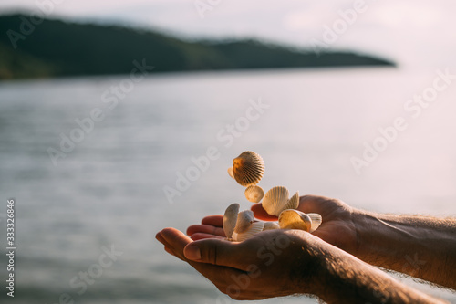 Men's hands toss a full handful of shells at sunset