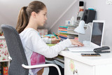 Dziewczynka pisze na laptopie zadanie