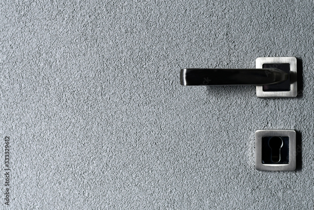 Metal handle on plastered grey door background. Copy space. Metal handle on plastered grey door background. Copy space.