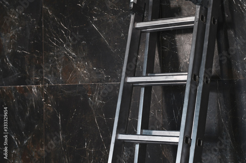 Metal ladder at marble grey wall. Copy space.