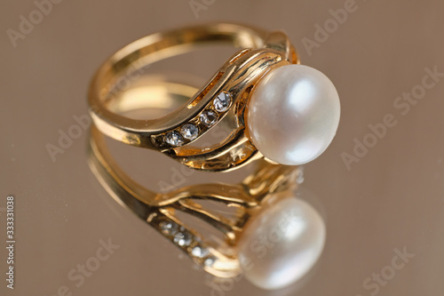 Golden ring with pearls on a glass table.