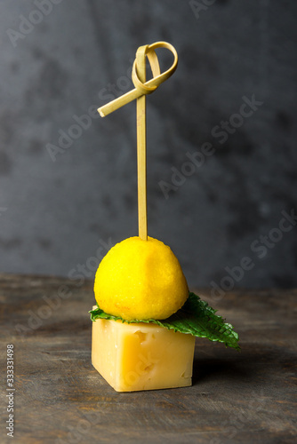 tasty canapes with cheese on a small skewer on a gray background. Vertical frame