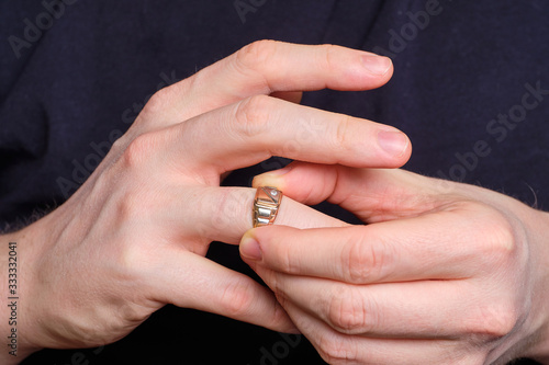 A man takes off a wedding ring from a finger of his hand.