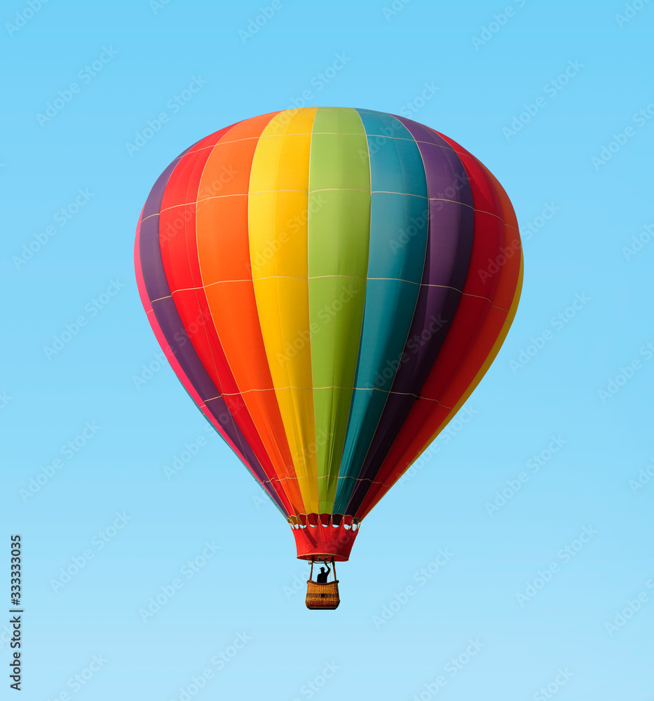Rainbow colored hot-air balloon floating against a blue sky Rainbow colored hot-air balloon floating against a blue sky