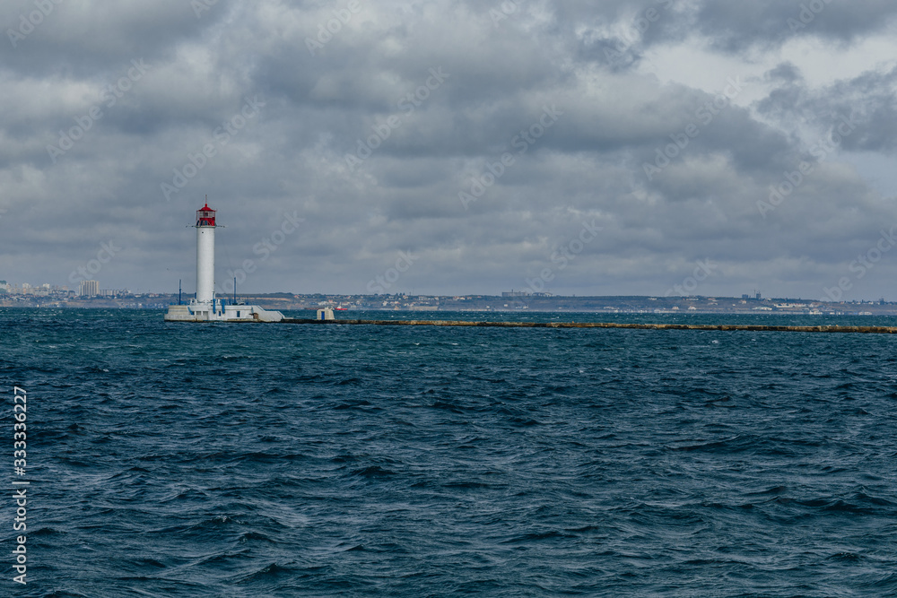 old lighthouse against the background of clouds and the sea in the seaport of Odessa