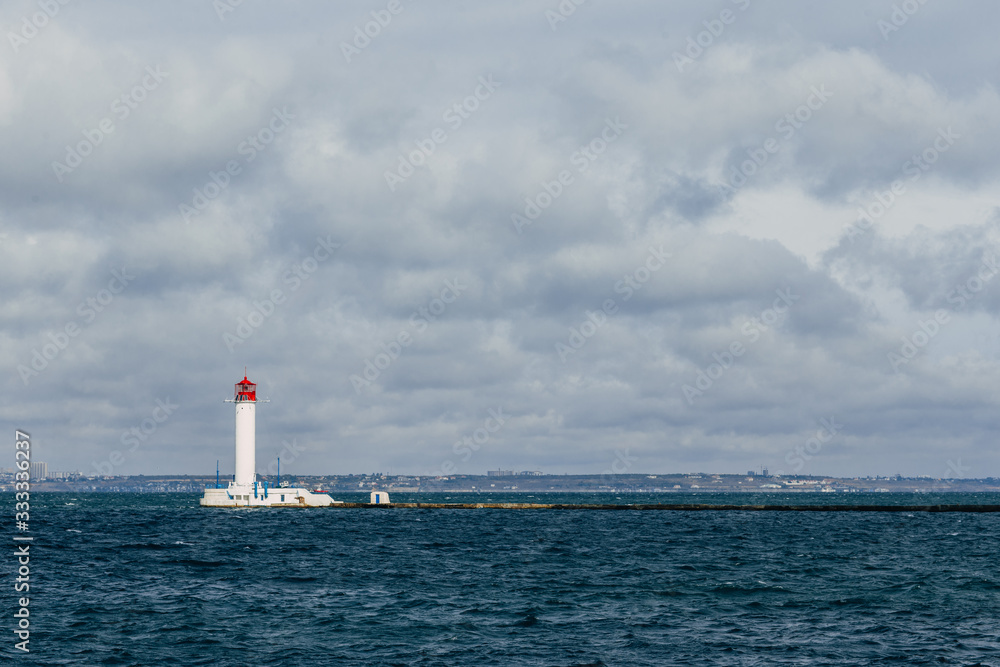 old lighthouse against the background of clouds and the sea in the seaport of Odessa