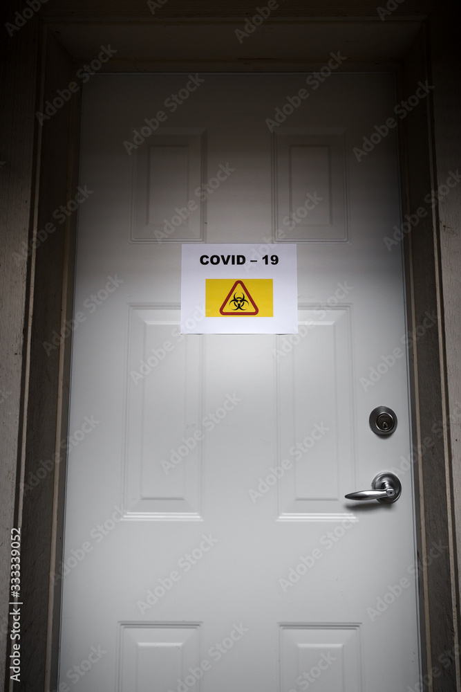 A self isolating residence with a quarantine sign on the front door warning of the Covid-19 virus. A self isolating residence with a quarantine sign on the front door warning of the Covid-19 virus.