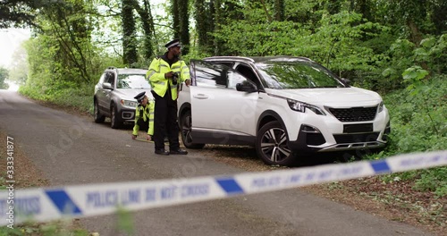 4K Policeman taking photos of a car at crime scene cordoned off with tape. Slow motion.