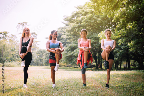 Group of sporty young women doing workout at public park in the morning,Slim woman warming up body at outdoor