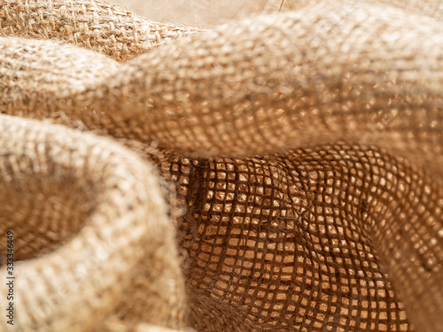 Crumpled baline, close up view, an abstract background. Texture of brown burlap textile. Brown sackcloth. Selective soft focus. Blurred background