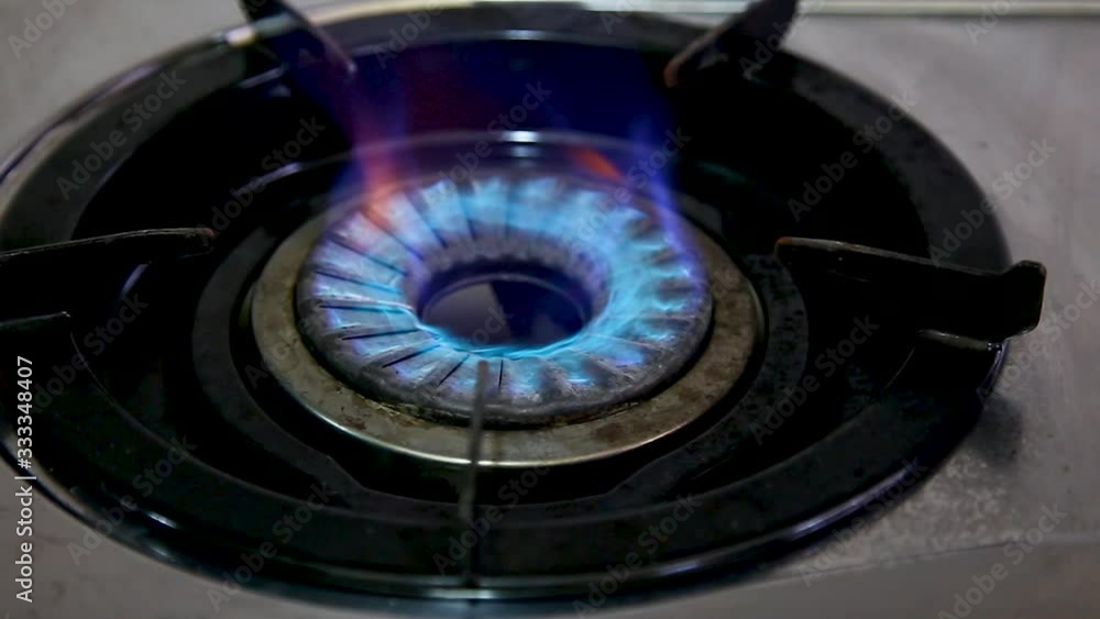 Stove top burner igniting into a blue cooking flame Stove top burner igniting into a blue cooking flame