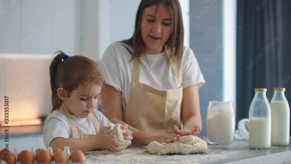 Mother and daughter cooking with dough mold in kitchen. Mother and daughter holding heart-shaped dough mold. Sculpt the dough with your hands to make blanks for pizza or pie, cookies Mother and daughter cooking with dough mold in kitchen. Mother and daughter holding heart-shaped dough mold. Sculpt the dough with your hands to make blanks for pizza or pie, cookies
