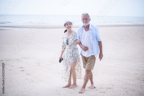 Retired couple walking on the beach.happy senior man and woman  holding hands together with love and care in romantic mood.Positive relationship of old people concept