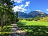 A view from the tee box looking down a tough par 4 lines with trees and the rocky mountains in the background.  It is a beautiful sunny day playing golf in Kananaskis.