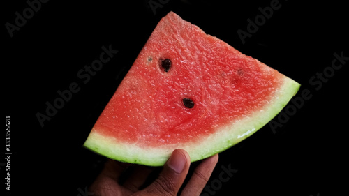 The man holding the watermelon with slices isolated on black background