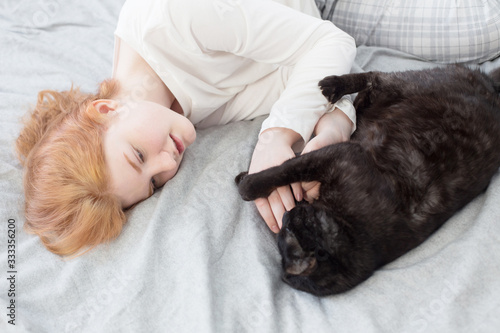 beautiful teenager girl with black cat on bed at home