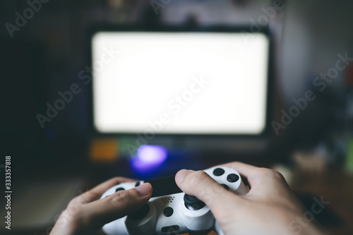 Adult hand hold joystick playing a game online with friend.