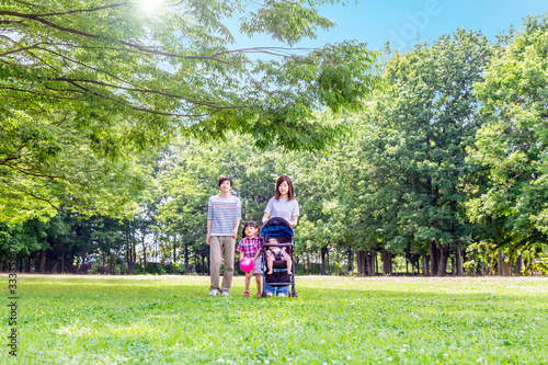 新緑の木々を背景に公園を散歩する幸せな家族イメージ