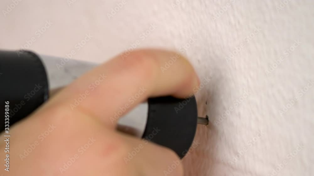 Child (boy) is learning work with nail and hammer. Decoration and renovation room, little helper, housework and children concept. Closeup child's hand, nail in white wall Child (boy) is learning work with nail and hammer. Decoration and renovation room, little helper, housework and children concept. Closeup child's hand, nail in white wall