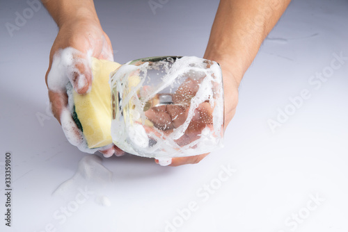 washing clear glass by bare hand and sponge foam on white background stock photo