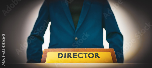 Принти на полотні School principle in  bluejacket stands next to the position office plate on the table with title - Director
