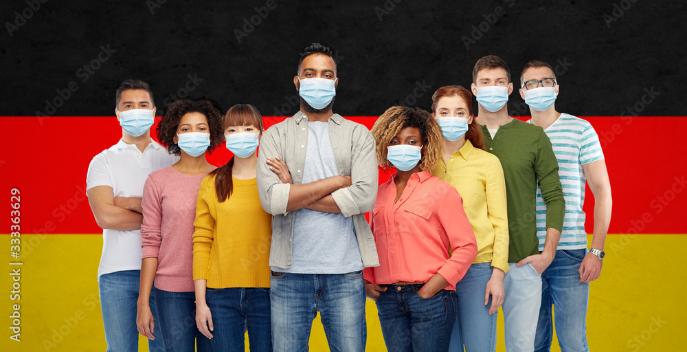 Obraz premium health, safety and pandemic concept - group of people wearing protective medical masks for protection from virus over german flag background
