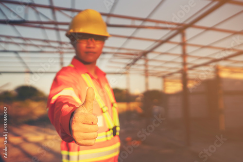 Engineer wear a hard helmet and show thumb up at construction site