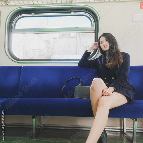 Portrait of a beautiful, young and fashionable Thai Asian woman sitting in a clean train.