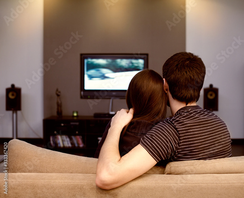 Self-isolation in a quarantine house of a young couple during a coronavirus pandemic. A man and a girl are watching TV.